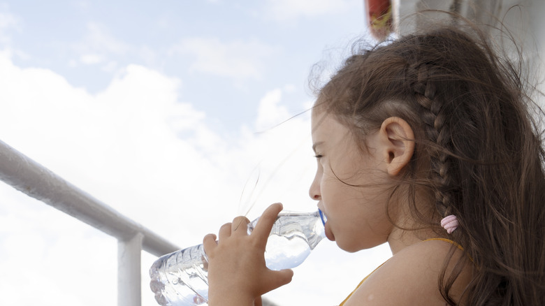 child drinks water on deck of ship