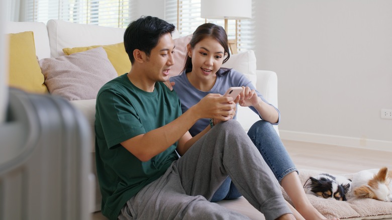 couple with luggage looking at phone