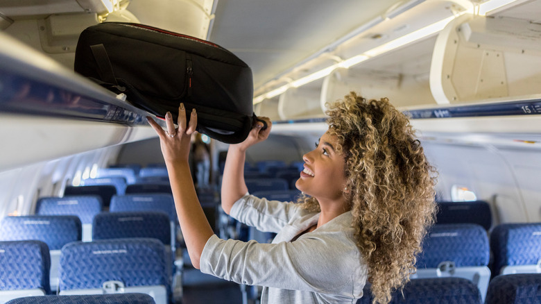 Woman putting carry-on in bin