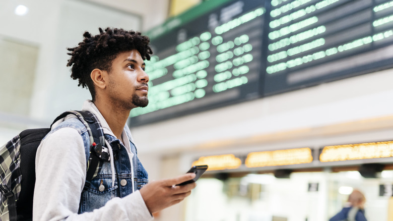 Man in airport looks at boards