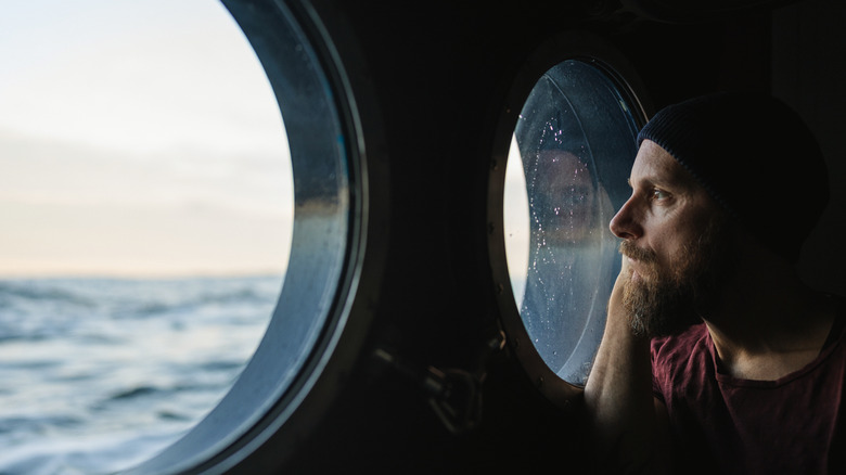 A man looking out a porthole