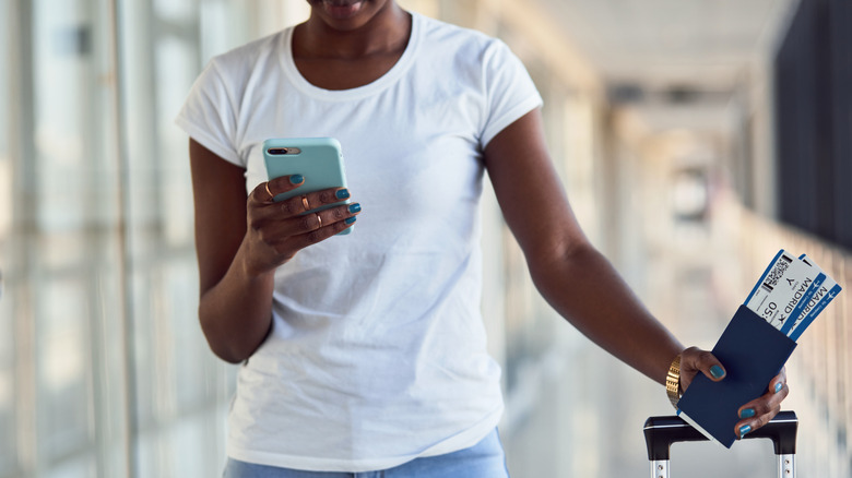 Woman holding passport and checking phone