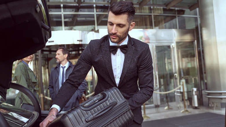 Man in a tuxedo loads a car