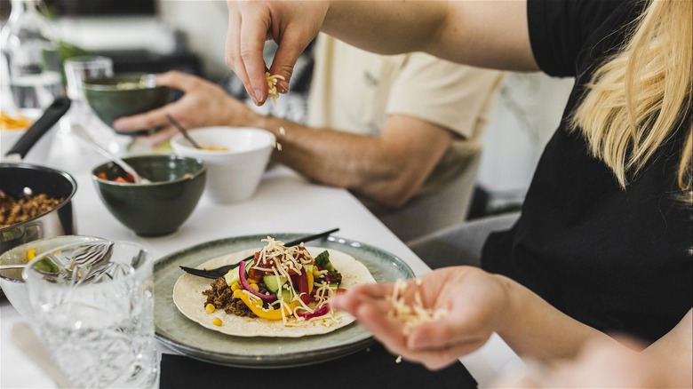 Woman adding toppings to taco 