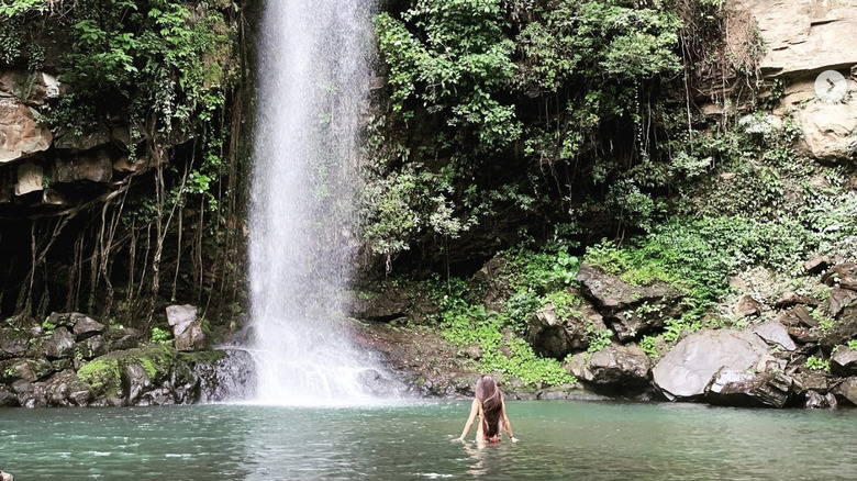 Woman standing below La Cangreja Waterfall